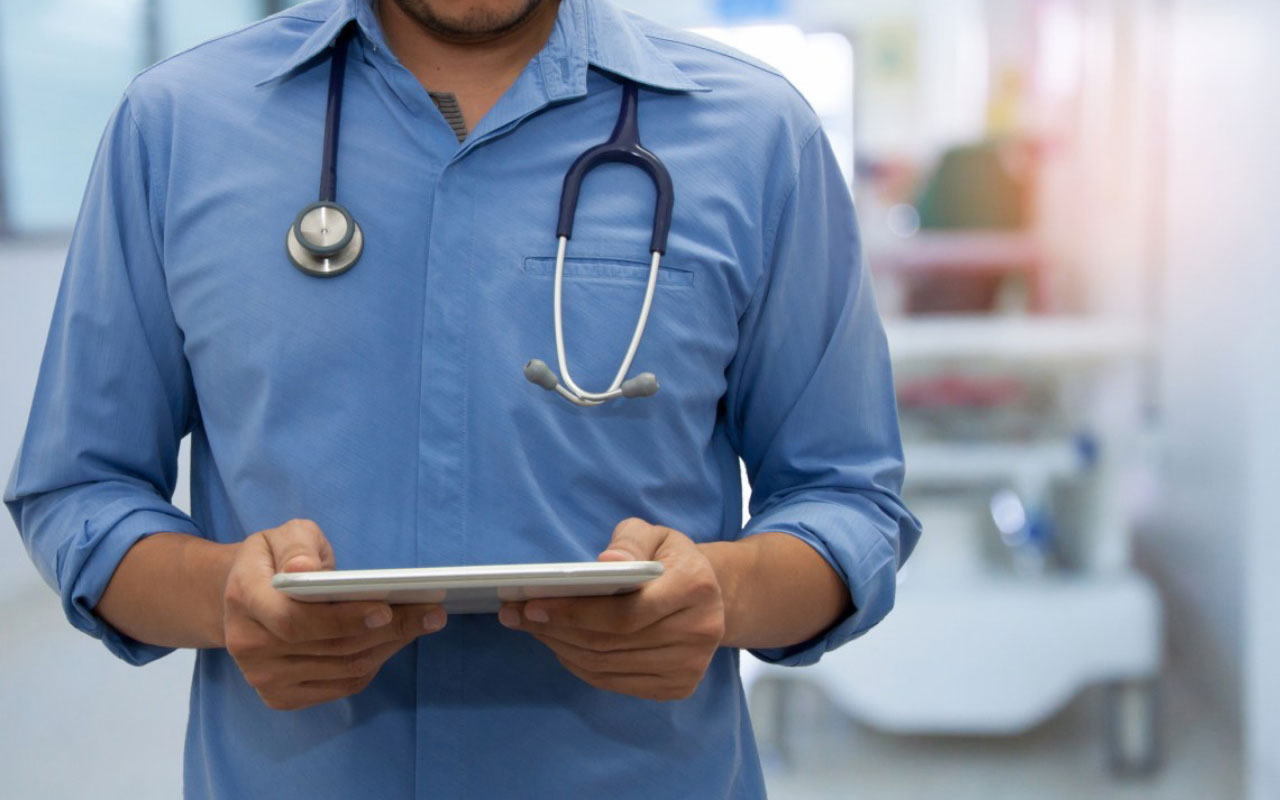 A doctor completing training in healthcare data solutions on a tablet.