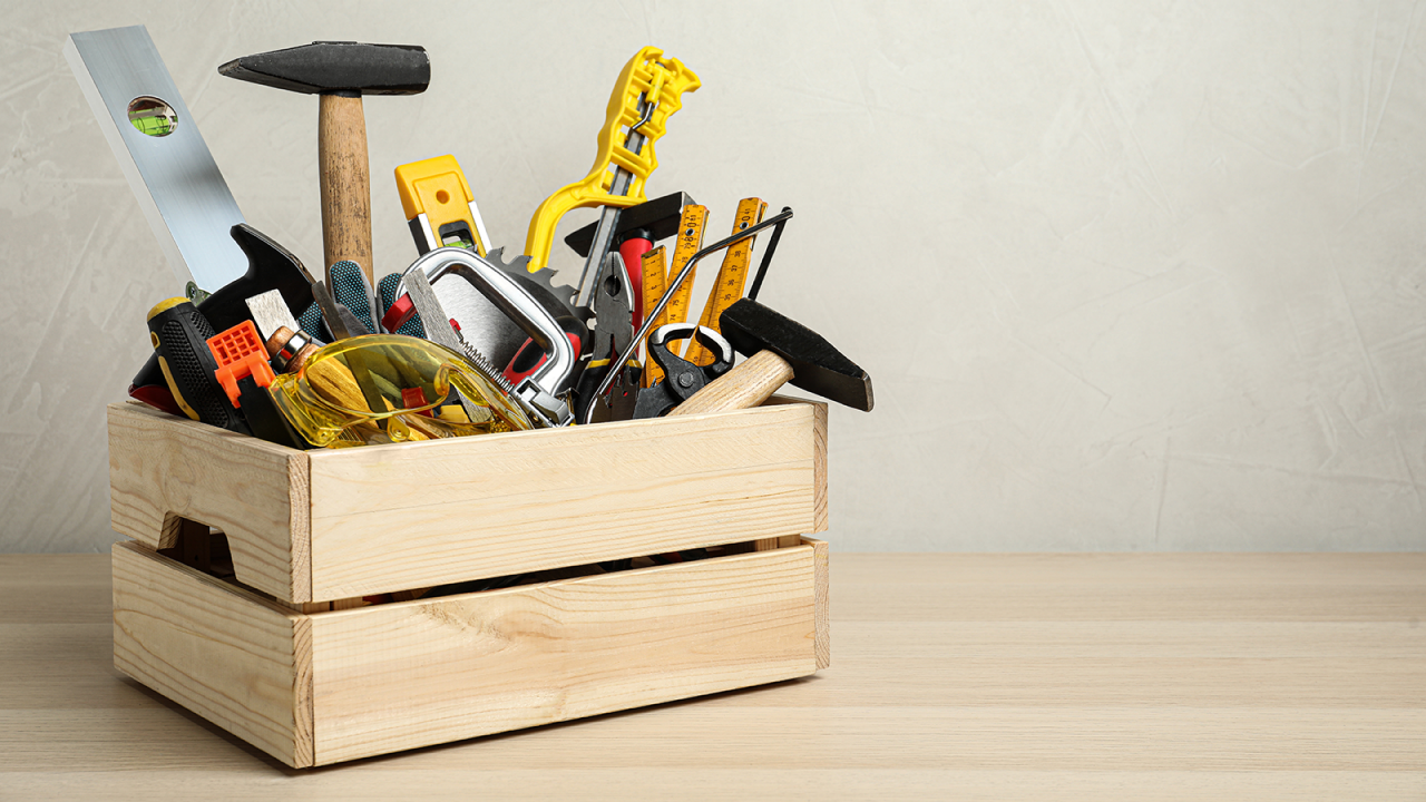 Caisse remplie d’outils de menuiserie sur une table en bois.